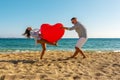 Young couple having fun on the beach with a big heart balloon. Summer love concept Royalty Free Stock Photo