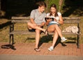 Young couple having fun on a bench in park while socializing over web Royalty Free Stock Photo