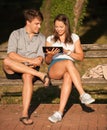 Young couple having fun on a bench in park while socializing over web Royalty Free Stock Photo