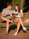 Young couple having fun on a bench in park while socializing over web Royalty Free Stock Photo