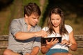 Young couple having fun on a bench in park while socializing over web Royalty Free Stock Photo