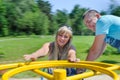 Young couple having fun on carousel on playground Royalty Free Stock Photo