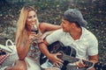 Young couple having fun with guitar and flirting during picnic in the park Royalty Free Stock Photo