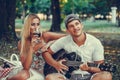 Young couple having fun with guitar and flirting during romantic picnic in the park Royalty Free Stock Photo