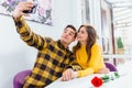 Young couple having fun, making different grimaces and postures, while taking selfie with mobile phone in a cafe. Royalty Free Stock Photo