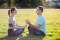 Young couple having fun outdoors. Man and woman meditating together outside on field with green grass at sunrise Royalty Free Stock Photo