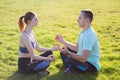 Young couple having fun outdoors. Man and woman meditating together outside on field with green grass at sunrise Royalty Free Stock Photo