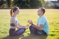 Young couple having fun outdoors. Man and woman meditating together outside on field with green grass at sunrise Royalty Free Stock Photo