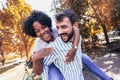 Couple having fun in park on autumn day. Handsome man giving piggy back to his girlfriend Royalty Free Stock Photo