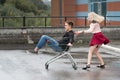 Young couple having fun on shopping trolley. Happy woman pushing shopping cart with her boyfriend inside Royalty Free Stock Photo