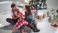 A young couple having fun with Xmas presents at home. Christmas, relationship, love, together