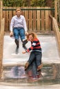 Young couple having a lot of fun on a big metal slide in the woo