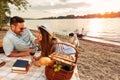 Young couple having a picnic at the beach. Lying on the picnic blanket, drinking red wine Royalty Free Stock Photo