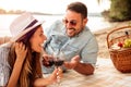 Young couple having a picnic at the beach. Lying on the picnic blanket, drinking wine and talking Royalty Free Stock Photo