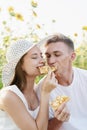 Young couple having picnic on sunflower field at sunset, biting a piece of pizza together Royalty Free Stock Photo