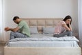 Young couple having relationship difficulties, sitting on opposite sides of bed, ignoring each other at home Royalty Free Stock Photo