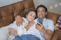 Young couple having relax together using mobile phone laying on the sofa in indoor relaxation leisure activity together. Black boy Royalty Free Stock Photo