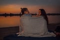 Young couple having a romantic date by the river, covered with blanket Royalty Free Stock Photo