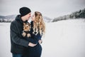 Young couple having a walk with their dog in snowy countryside