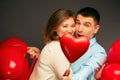 Young couple with heart shaped red balloons near grey wall Royalty Free Stock Photo