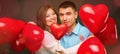 Young couple with heart shaped red balloons near grey wall Royalty Free Stock Photo