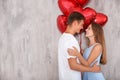 Young couple with heart shaped red balloons near grey wall Royalty Free Stock Photo