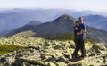 Young couple hike in Carpathian mountains. Man and woman standing on mountain top looking at beautiful landscape below. High rocky Royalty Free Stock Photo