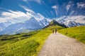 Young couple hiking in panorama trail leading to Kleine Scheidegg from Mannlichen with Eiger, Monch and Jungfrau mountain