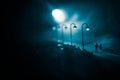 Young couple holding each other hands. Slowly walking under white street lights in night. Dark time. Peaceful atmosphere in mist. Royalty Free Stock Photo