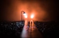 Young couple holding each other hands. Slowly walking under white street lights in night. Dark time. Peaceful atmosphere in mist. Royalty Free Stock Photo