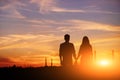 Young couple is holding hands on a background sunset silhouette Royalty Free Stock Photo