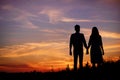 Young couple is holding hands on a background sunset silhouette Royalty Free Stock Photo