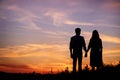 Young couple is holding hands on a background sunset silhouette Royalty Free Stock Photo