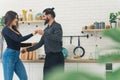 Young couple holding hands dancing together in the kitchen. White woman with dark long hair and dark-haired man with a Royalty Free Stock Photo