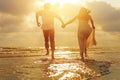 Young couple holding hands and running on the beach and sunset Royalty Free Stock Photo