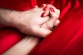 Young couple holding hands sensually on red silk bed Royalty Free Stock Photo