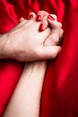 Young couple holding hands sensually on red silk bed Royalty Free Stock Photo