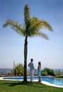 Young couple holding hands under a palm tree in the sun. Royalty Free Stock Photo