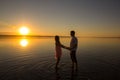 Young couple is holding hands in the water on summer beach. Sunset over the sea. . Two silhouettes against the sun. Calm and still Royalty Free Stock Photo
