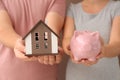 Young couple holding house model and piggy bank, closeup. Mortgage concept Royalty Free Stock Photo