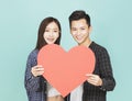 Young couple holding red heart together standing over blue background Royalty Free Stock Photo