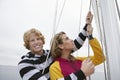 Young Couple Holding Rigging On Sailboat