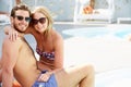 Young Couple On Holiday Relaxing By Swimming Pool Royalty Free Stock Photo