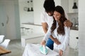 Young couple at home doing hosehold chores and ironing