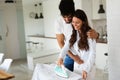 Young couple at home doing hosehold chores and ironing