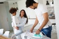 Young couple at home doing hosehold chores and ironing