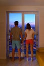Young couple at home looking at the evening panorama of the city thru window Royalty Free Stock Photo