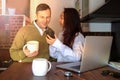 Young couple at home near the laptop are drinking coffee and laughing. Happy international couple make online purchase. Royalty Free Stock Photo