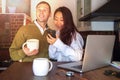 Young couple at home near the laptop are drinking coffee and laughing. Happy international couple make online purchase. Royalty Free Stock Photo