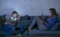 Young couple at home sofa couch smiling happy together but separated ignoring each other concentrated on mobile phone in internet Royalty Free Stock Photo